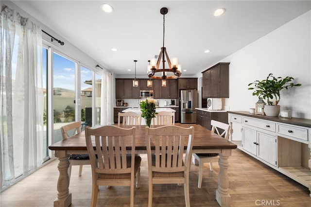 dining area with light wood-style flooring, an inviting chandelier, and recessed lighting