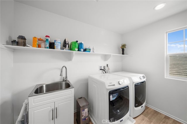 clothes washing area with washing machine and clothes dryer, recessed lighting, a sink, light wood-style floors, and cabinet space