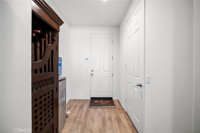 doorway to outside featuring baseboards and light wood finished floors