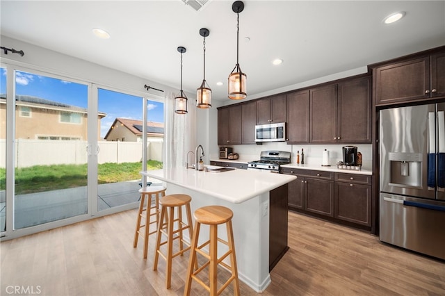 kitchen with dark brown cabinetry, a sink, light wood-type flooring, and appliances with stainless steel finishes