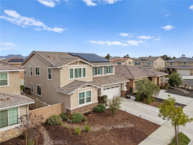 view of front of property with stucco siding, fence, stone siding, a residential view, and driveway