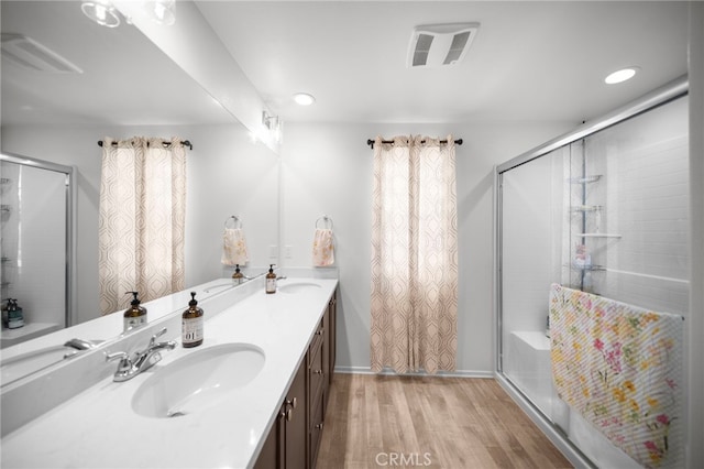 full bathroom with visible vents, a sink, a stall shower, and wood finished floors