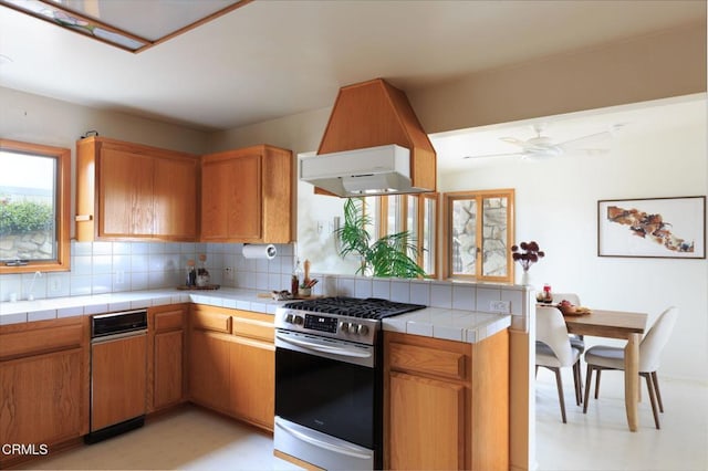 kitchen featuring backsplash, tile countertops, brown cabinetry, and stainless steel gas stove