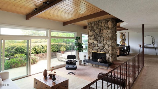 carpeted living area with a fireplace, wooden ceiling, and beamed ceiling
