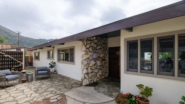 view of exterior entry featuring a mountain view, a patio area, stucco siding, and stone siding