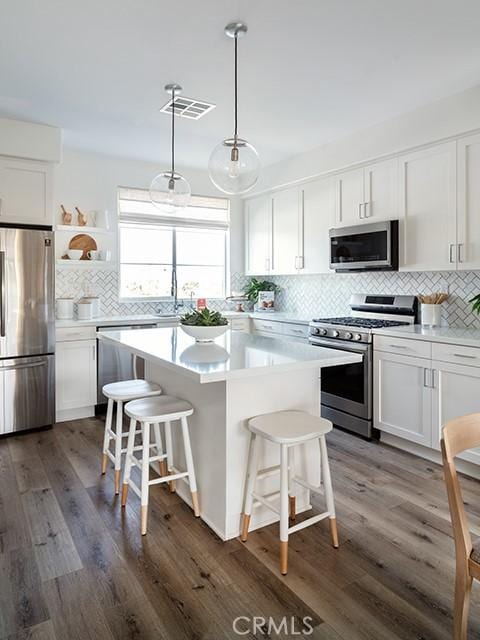 22305 Sage Ct, Torrance, CA 90502 - kitchen with appliances with stainless steel finishes, backsplash, a breakfast bar, and white cabinetry