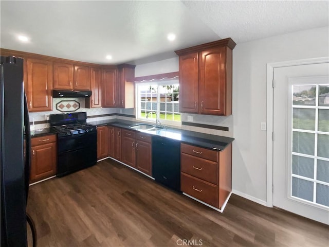 4739 Belmont Pl, Chino, CA 91710 - kitchen with black appliances, under cabinet range hood, a sink, dark countertops, and dark wood-type flooring