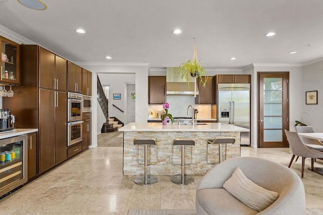 6497 Wayfinders Ct, Carlsbad, CA 92011 - kitchen with appliances with stainless steel finishes, wall chimney exhaust hood, crown molding, a kitchen breakfast bar, and recessed lighting