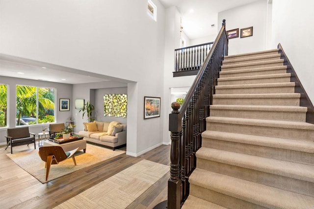 6497 Wayfinders Ct, Carlsbad, CA 92011 - staircase featuring wood finished floors, a high ceiling, and recessed lighting