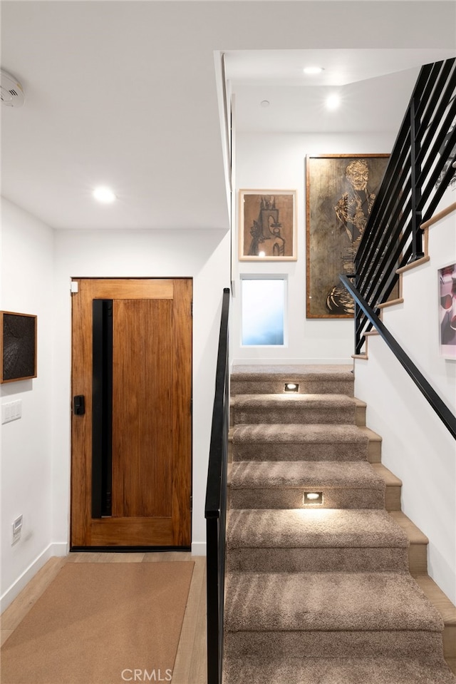 staircase featuring baseboards and recessed lighting