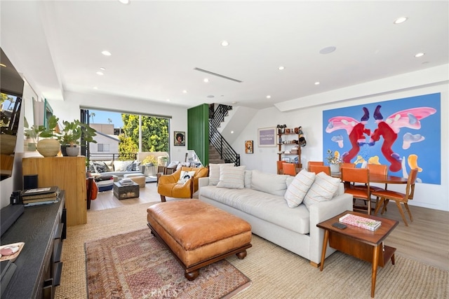 living room featuring recessed lighting, light wood-style flooring, and stairway