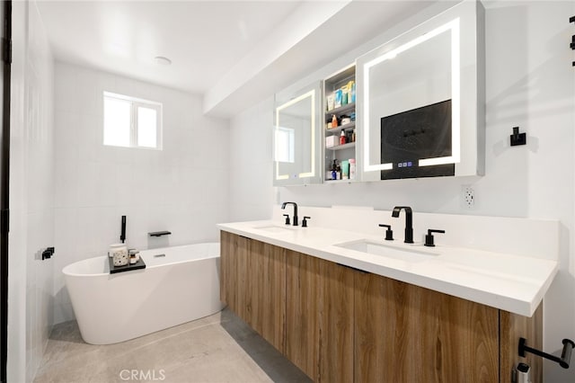 full bathroom with a soaking tub, double vanity, a sink, and tile walls