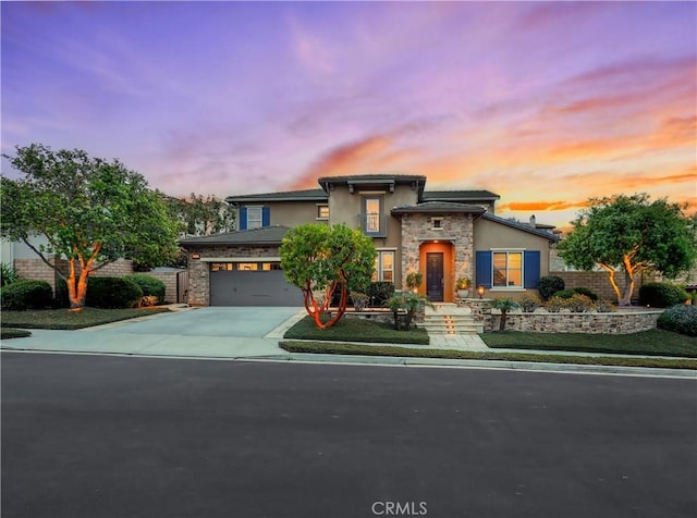 view of front of home featuring driveway, stone siding, and stucco siding