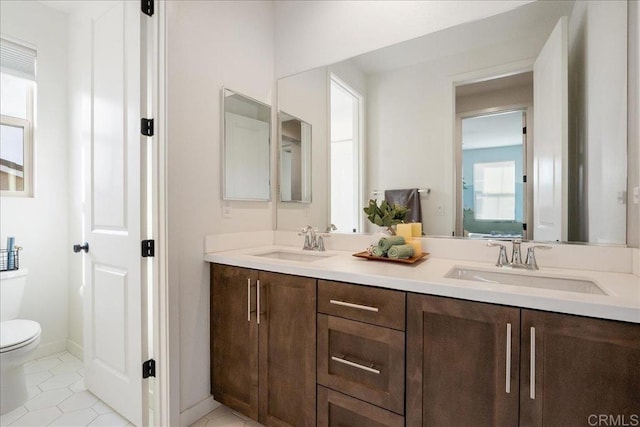 bathroom with double vanity, tile patterned floors, toilet, and a sink