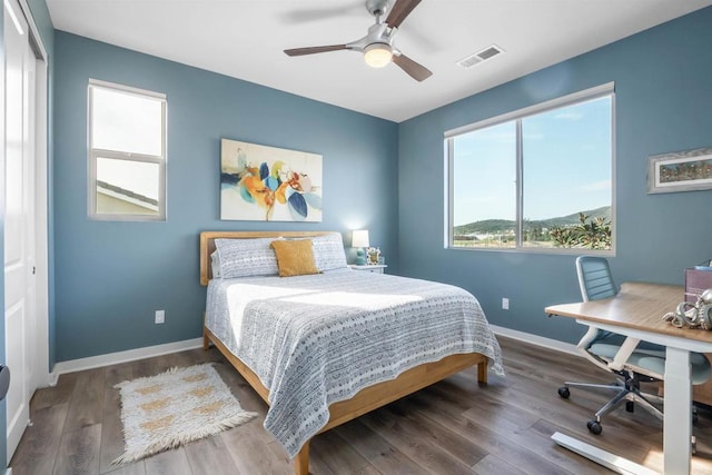 bedroom with baseboards, a ceiling fan, wood finished floors, and visible vents