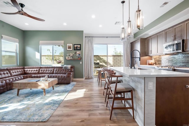 living area with light wood-type flooring, a ceiling fan, visible vents, and recessed lighting