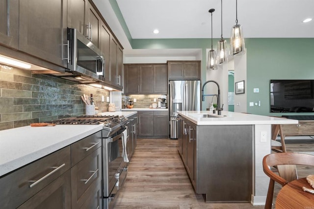 kitchen featuring light countertops, dark brown cabinets, stainless steel appliances, and a sink