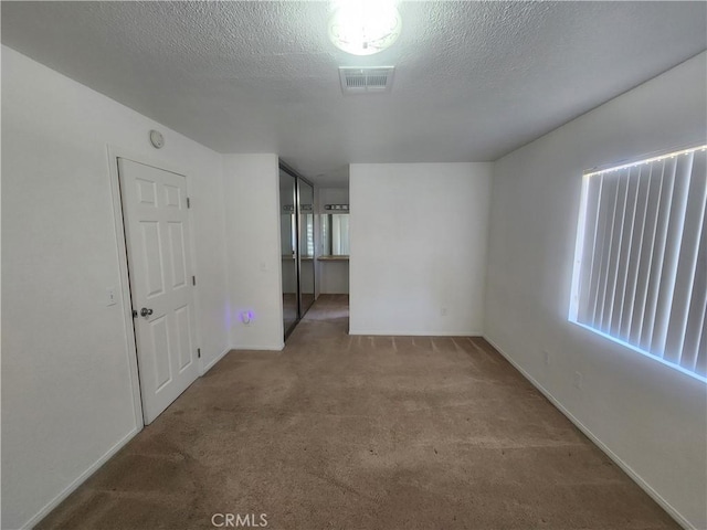 carpeted empty room featuring baseboards and visible vents