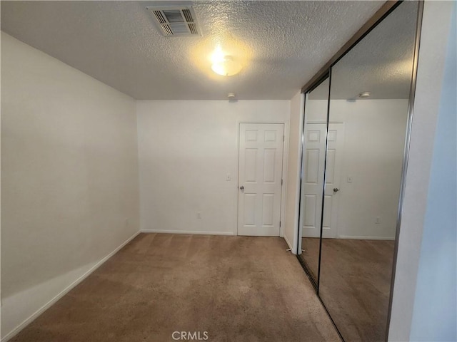 unfurnished bedroom with carpet, visible vents, a closet, baseboards, and a textured ceiling