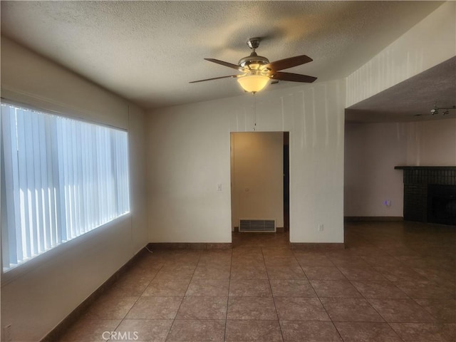 interior space with tile patterned floors, a ceiling fan, visible vents, and a textured ceiling