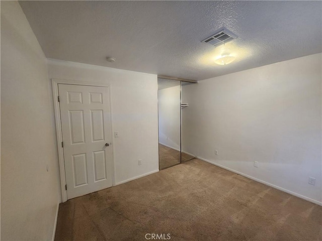 interior space with baseboards, visible vents, carpet, and a textured ceiling