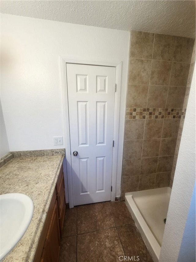 full bathroom featuring vanity, a textured ceiling, and a stall shower