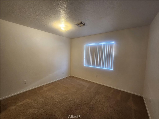 carpeted spare room with a textured ceiling, visible vents, and baseboards