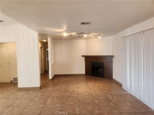 unfurnished living room with a textured ceiling, visible vents, and a fireplace