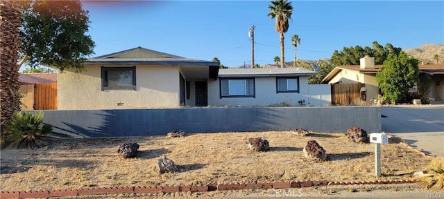 ranch-style home featuring stucco siding and fence