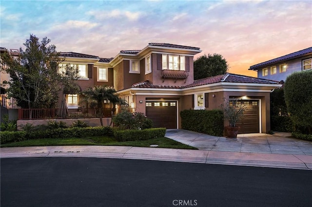 mediterranean / spanish-style house with a tiled roof, driveway, and stucco siding