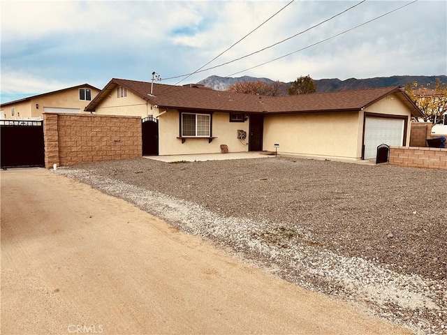 6252 Maloof Ave, Fontana, CA 92336 - ranch-style home featuring a garage, stucco siding, fence, a gate, and a mountain view