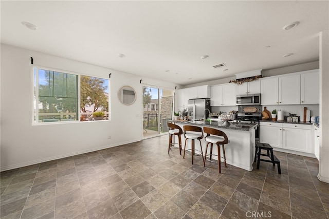 kitchen with visible vents, baseboards, dark countertops, appliances with stainless steel finishes, and a breakfast bar area