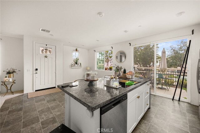 kitchen with visible vents, dishwasher, a kitchen island, white cabinetry, and a sink