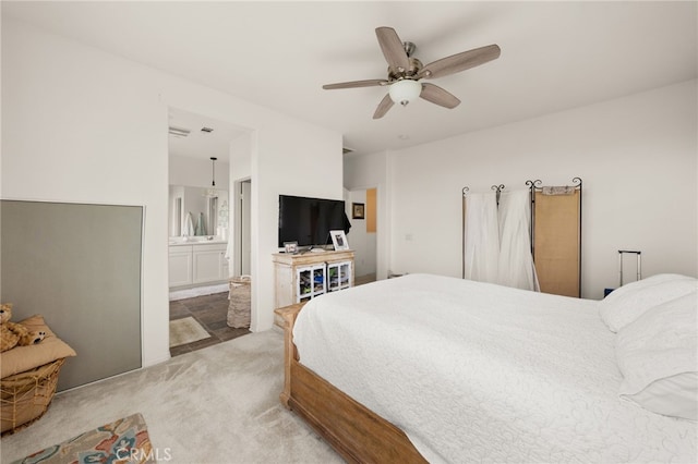 bedroom featuring light carpet, connected bathroom, and ceiling fan