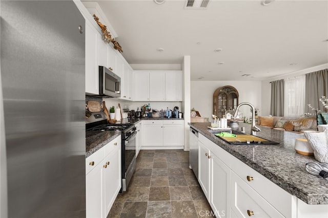 kitchen featuring a sink, white cabinetry, dark stone countertops, and appliances with stainless steel finishes