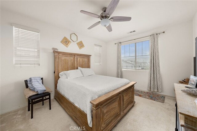 bedroom with light carpet, visible vents, and ceiling fan