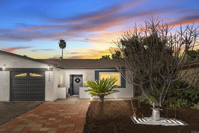 view of front facade featuring stucco siding, driveway, and a garage