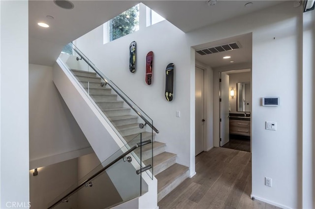 staircase featuring wood finished floors, visible vents, and recessed lighting
