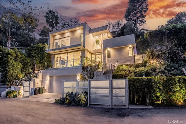 contemporary house with concrete driveway, stucco siding, a fenced front yard, and a garage
