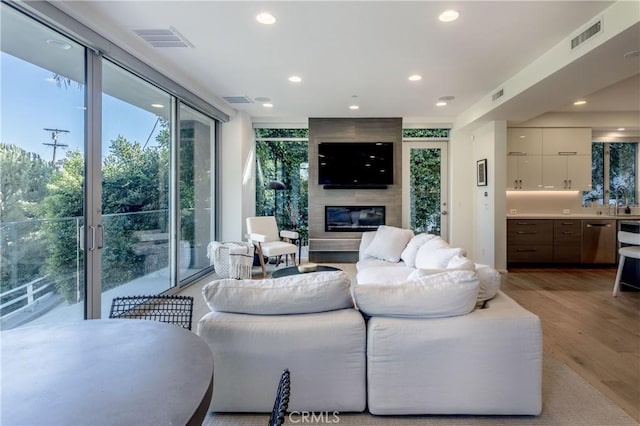 living room with wood finished floors, a large fireplace, and visible vents