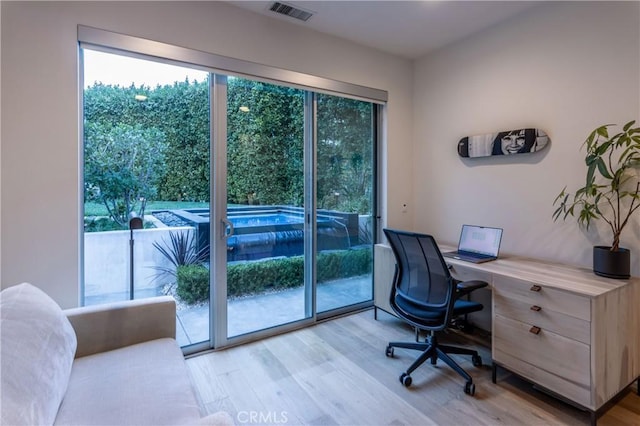 office area with light wood finished floors and visible vents