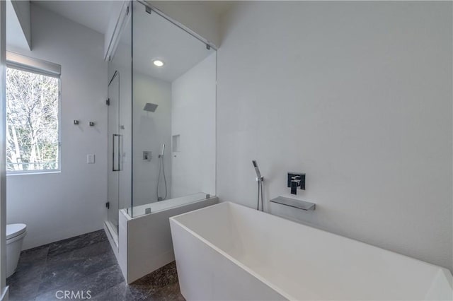 bathroom with toilet, a stall shower, and a freestanding tub