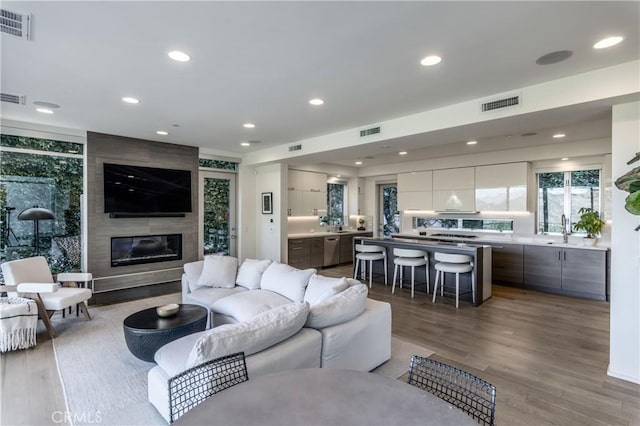 living area featuring recessed lighting, visible vents, a large fireplace, and wood finished floors