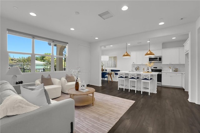 living area featuring recessed lighting, baseboards, visible vents, and dark wood-style floors