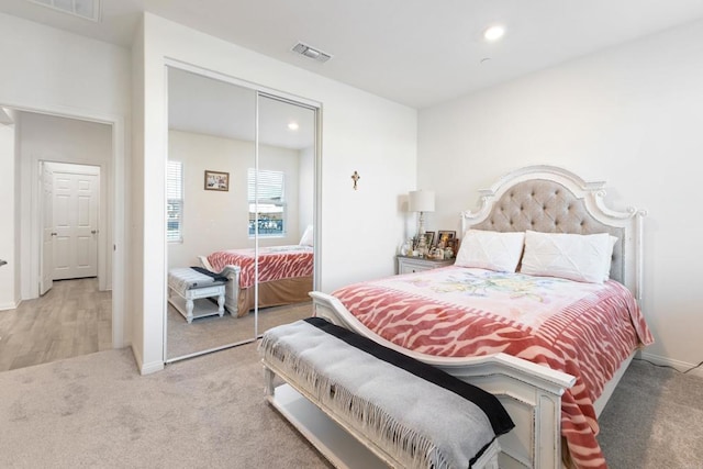 bedroom featuring a closet, light colored carpet, recessed lighting, and visible vents