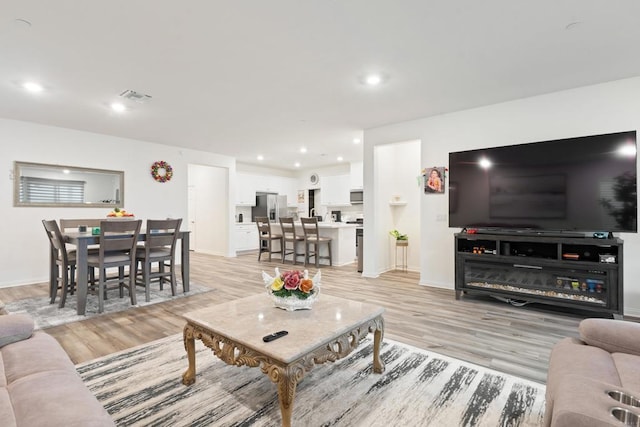 living area with visible vents, recessed lighting, light wood-style flooring, and baseboards