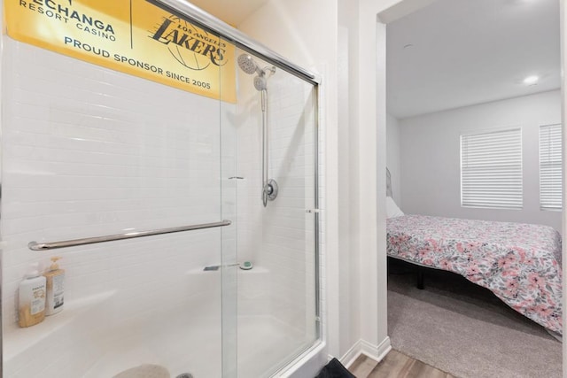 bathroom featuring baseboards, wood finished floors, ensuite bathroom, and a stall shower