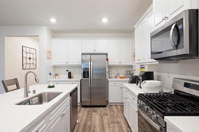 kitchen with light countertops, a sink, white cabinets, and stainless steel appliances