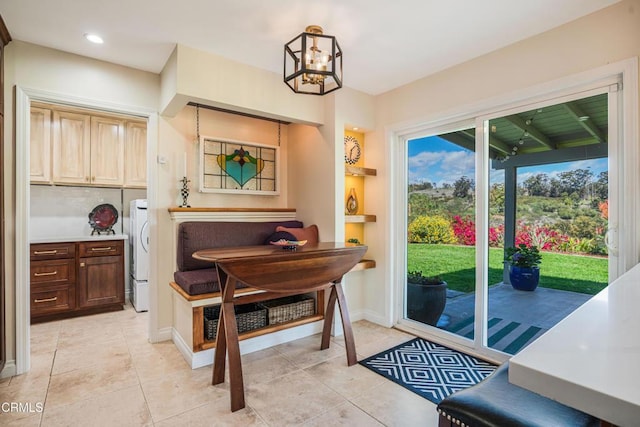 entryway with baseboards, a chandelier, light tile patterned floors, and washer / dryer