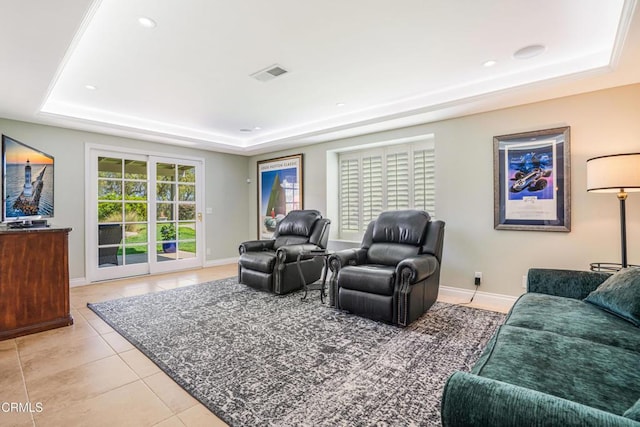 living area with light tile patterned floors, baseboards, visible vents, and a raised ceiling